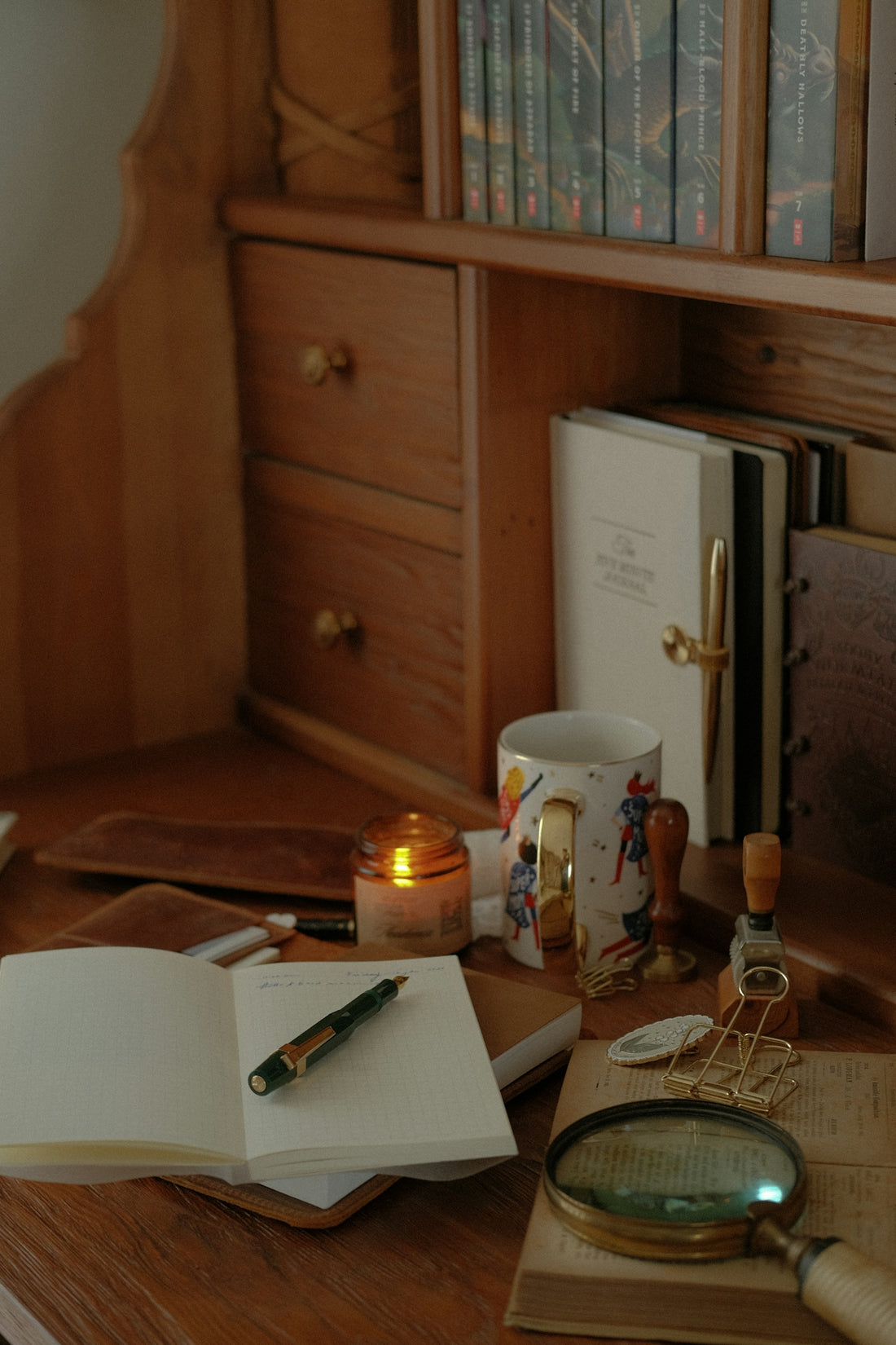 Desk with open journal, pen, candle, and magnifying glass